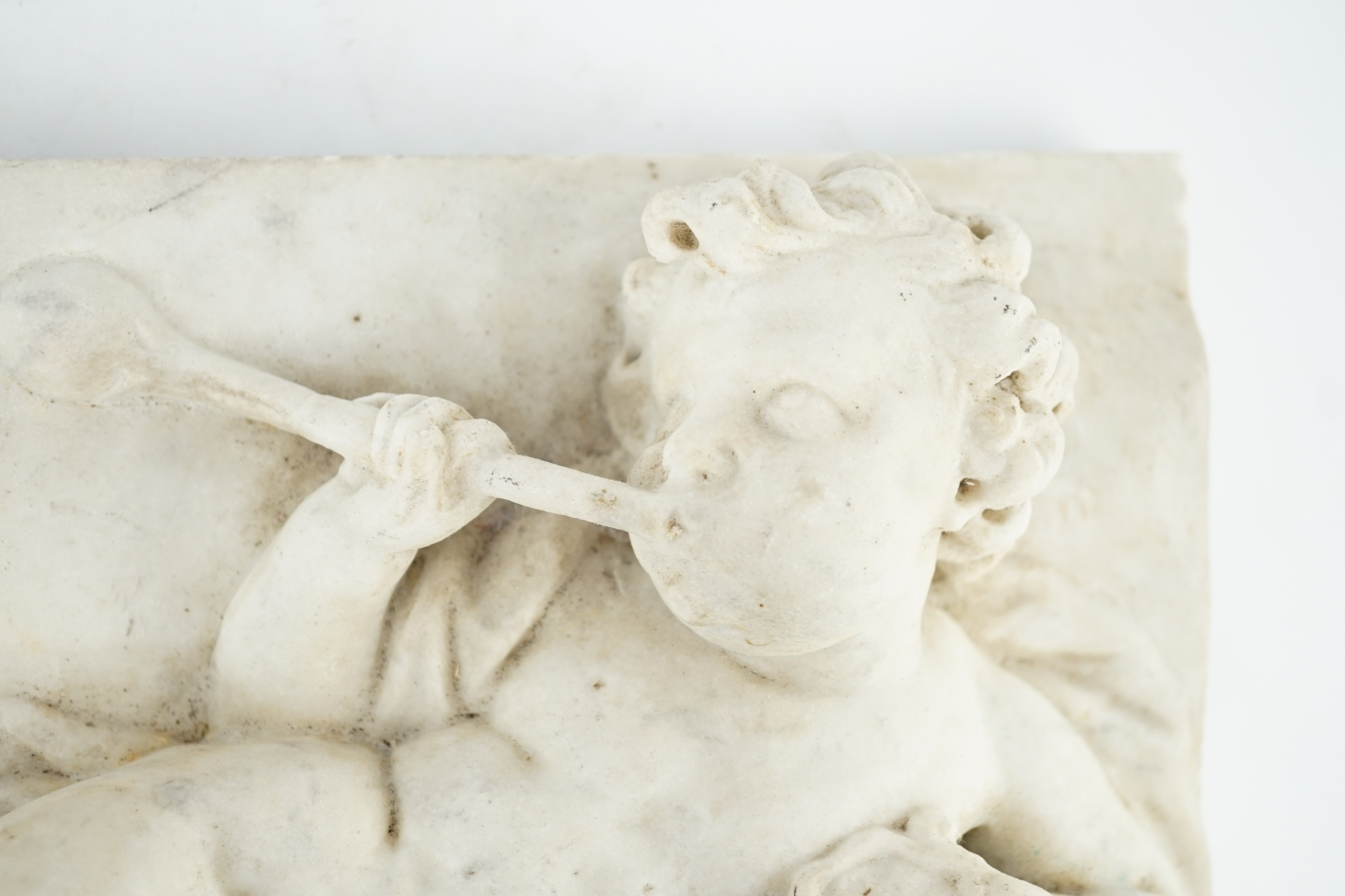 A 17th/18th century Italian marble plaque carved with a reclining cherub, 19.5 x 34.5cm